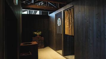 Un pasillo con paredes de madera, una planta en maceta y una puerta con un logo circular.