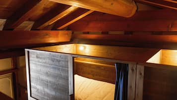 L’intérieur d’un chalet en bois, avec un lit en mezzanine, des poutres apparentes et une esthétique rustique.