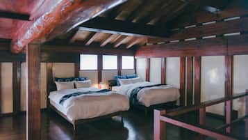 A room with two beds, wooden beams, and large windows.
