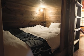 Une pièce de cabane en bois comprenant un lit, un luminaire suspendu et un banc en bois.