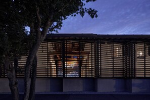 A modern building with a grid-like facade, large windows, and a tree in the foreground. - Bon-yado Uakita Nishimonai (Ugo)