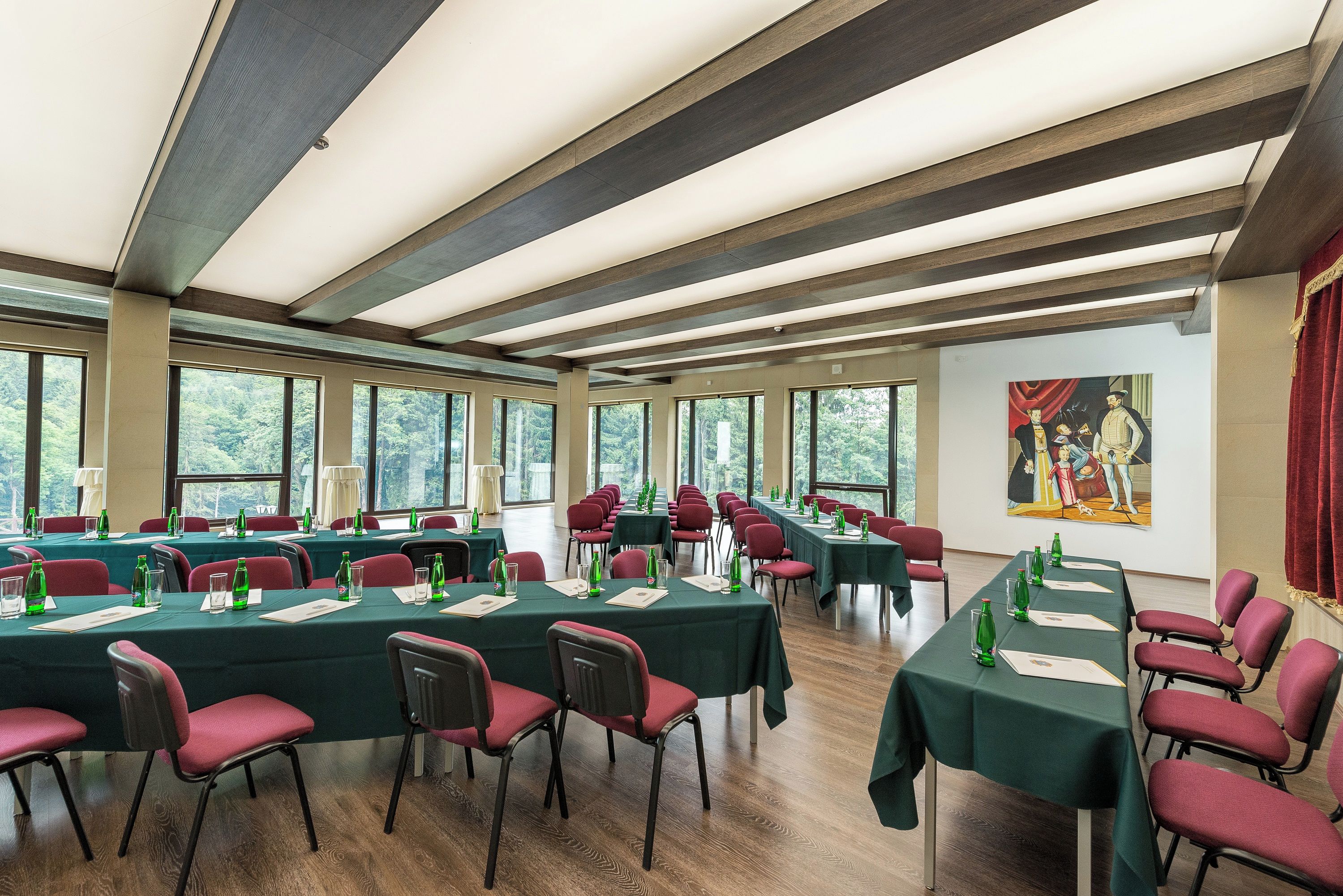 Un salón de conferencias con largas mesas, sillas y ventanas amplias.