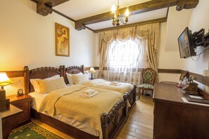 A bedroom with a double bed, a wooden nightstand, a desk, a chair, a television, and a painting on the wall. - Zámek Lužec Spa And Wellness Resort (Nejdek)