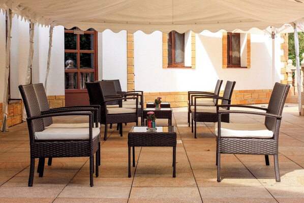 A covered outdoor seating area with wicker furniture and a tiled floor. - Zámek Lužec Spa And Wellness Resort (Nejdek)