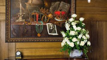 A framed painting with a clock, a vase of white flowers, and a wooden cabinet.