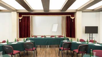 Ein Konferenzraum mit langem Tisch, Stühlen, einer Whiteboard und einer Projektionsleinwand.