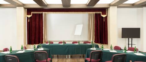 Een vergaderzaal met een lange tafel, stoelen, een whiteboard en een projectiescherm.