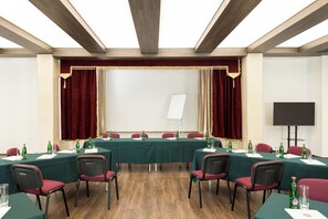 Une salle de conférence équipée d’une longue table, de chaises, d’un tableau blanc et d’un écran de projection.