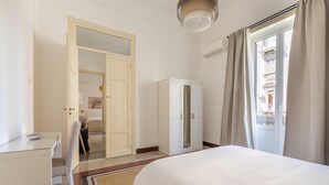 Una camera d'albergo con un letto, una scrivania, un armadio e una porta che dà su un'altra stanza.