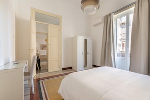 Ein Hotelzimmer mit Bett, Schreibtisch, Kleiderschrank und einer Tür zu einem anderen Raum.