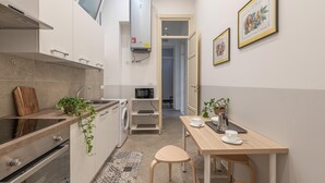 Una cucina compatta con forno a microonde, lavandino e un piccolo angolo ristoro con sgabelli.