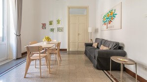 Un soggiorno con divano, tavolo da pranzo con sedie, lampada e una porta.