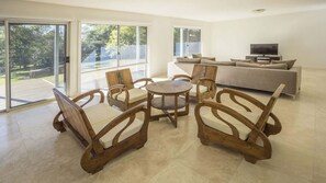Un salon spacieux avec une table ronde en bois et des chaises, un canapé et un téléviseur.