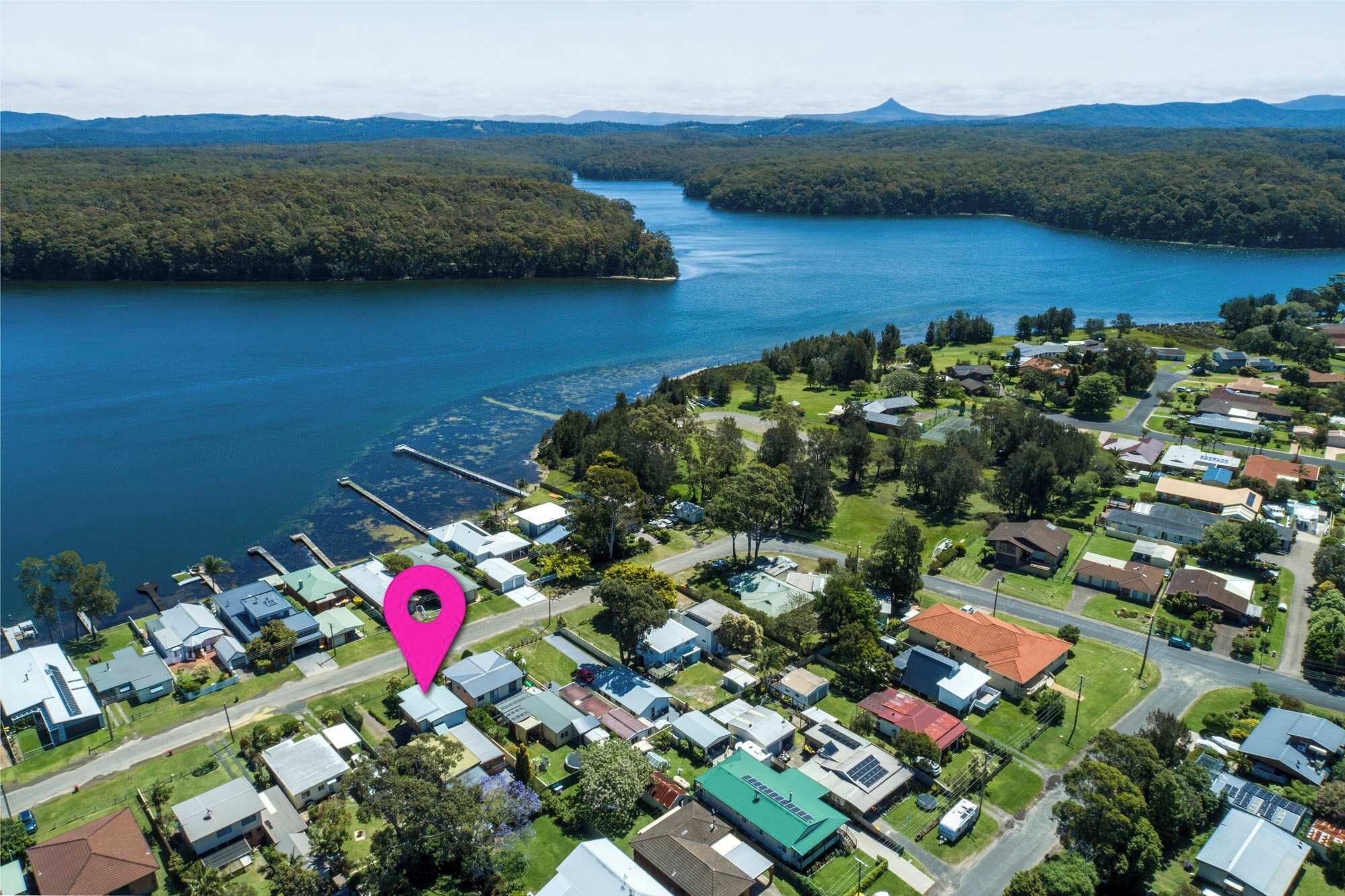 An aerial view of a residential area with houses, a dock, and a lake.
