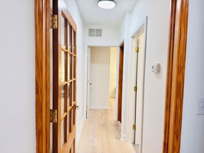 A hallway with wooden doors, white walls, and a light-colored floor.
