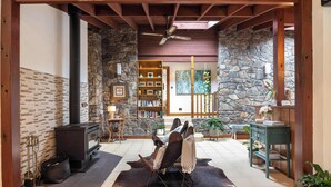 Ein gemütliches Wohnzimmer mit Steinwand, Kamin, Bücherregal und einer bequemen Sitzecke.