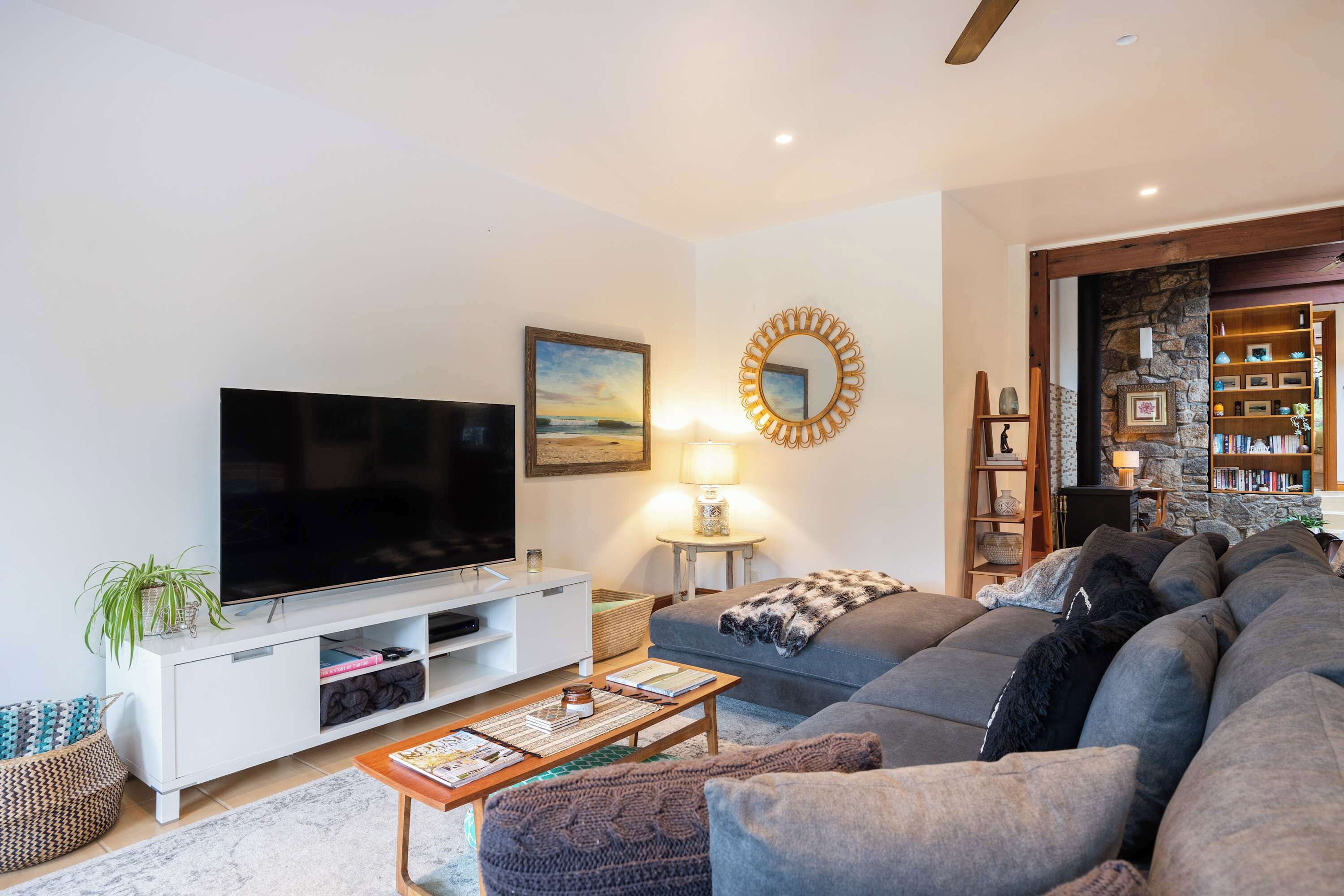 A modern living room with a flat-screen TV, a sofa, a coffee table, and a bookshelf.