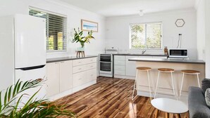 Eine moderne Küche mit weißen Schränken, einem Backofen, einer Mikrowelle und einer Bar mit Sitzgelegenheiten.