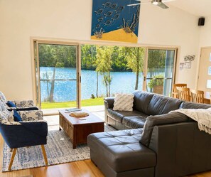 Uma sala de estar com vista para um lago, um ventilador de teto e uma janela ampla.