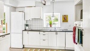 A kitchen with white cabinets, a refrigerator, a coffee maker, a sink, and a window with a plant. - 5 bedroom pet friendly home in Sjöbo (Sjöbo)