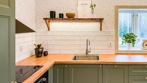 Una cocina con encimera de madera, pileta de acero inoxidable y ventana con vista a árboles.