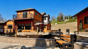 A multi-story building with a balcony, a stone retaining wall, and a gravel area with rocks. - .50 Acre Property - Spacious Living with Wood Accents - Sleeps up to 20 (Vernon)