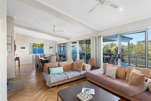 A spacious living area with a large sofa, a coffee table, and a dining area with chairs and a table. - Dream Weaver at Bawley Point (Bawley Point)