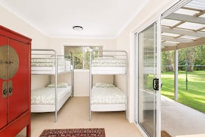 A room with bunk beds, a red cabinet, and a sliding glass door leading to a garden. - Dream Weaver at Bawley Point (Bawley Point)
