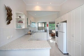 A modern kitchen with white cabinets, a granite countertop, and a built-in oven. - Dream Weaver at Bawley Point (Bawley Point)