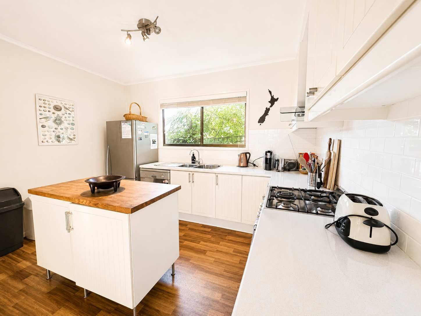 A modern kitchen with white cabinetry, a wooden island, a gas stove, and a window providing natural light.