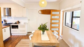 Une cuisine moderne avec des meubles blancs, une table à manger en bois et une grande fenêtre.