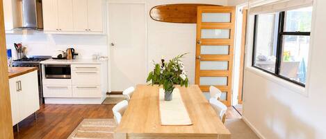 Une cuisine moderne avec des meubles blancs, une table à manger en bois et une grande fenêtre.