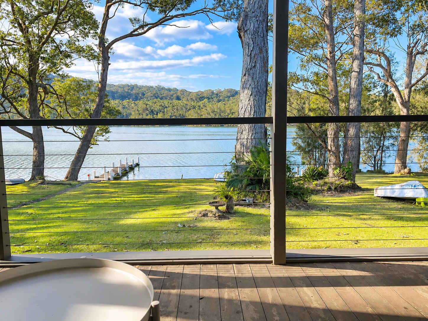 A deck with a view of a lake and forest.