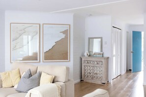 Ein Wohnzimmer mit einem beigen Sofa, einer Vitrine mit Dekoration und einer blauen Tür im Hintergrund.
