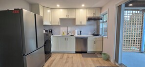 Eine moderne Küche mit weißen Schränken, einem Edelstahl-Kühlschrank, einem Geschirrspüler und einem Fenster mit Blick.