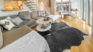 A modern living room with a sofa, coffee table, and a large black and white rug.
