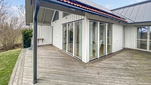 A modern house with a covered patio, large sliding glass doors, and a wooden deck.