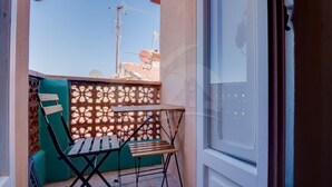 Ein Balkon mit Tisch und Stühlen, einem Zierzaun und wolkenlosem Himmel.