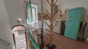 Eine Küche mit einem türkisblauen Kühlschrank, einer Holz-Baumskulptur und einer Treppe, die zu einer oberen Ebene führt.