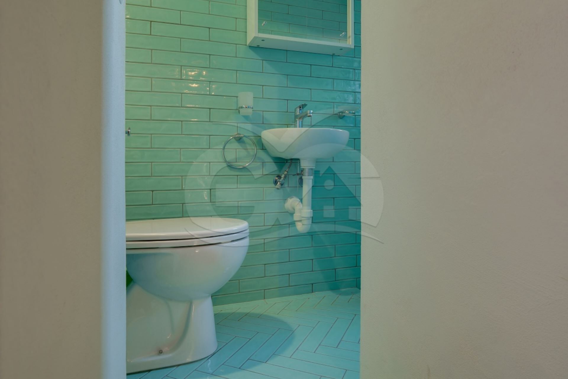 A bathroom with a toilet, a sink, and a tiled wall.