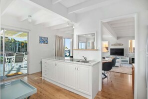 A modern kitchen with white cabinets, a built-in sink, and a dining area with a TV.