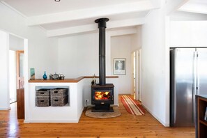 Eine moderne Küche mit Kaminofen, Edelstahlkühlschrank und Holzboden.