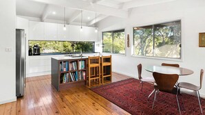 A modern kitchen with white cabinets, a wooden island, and a red rug. - Sea Forever at Kioloa (Kioloa)