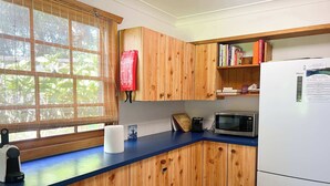 Cozinha com armários de madeira, micro-ondas, torradeira e geladeira.