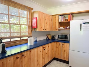 Cocina con gabinetes de madera, microondas, tostadora y refrigerador.