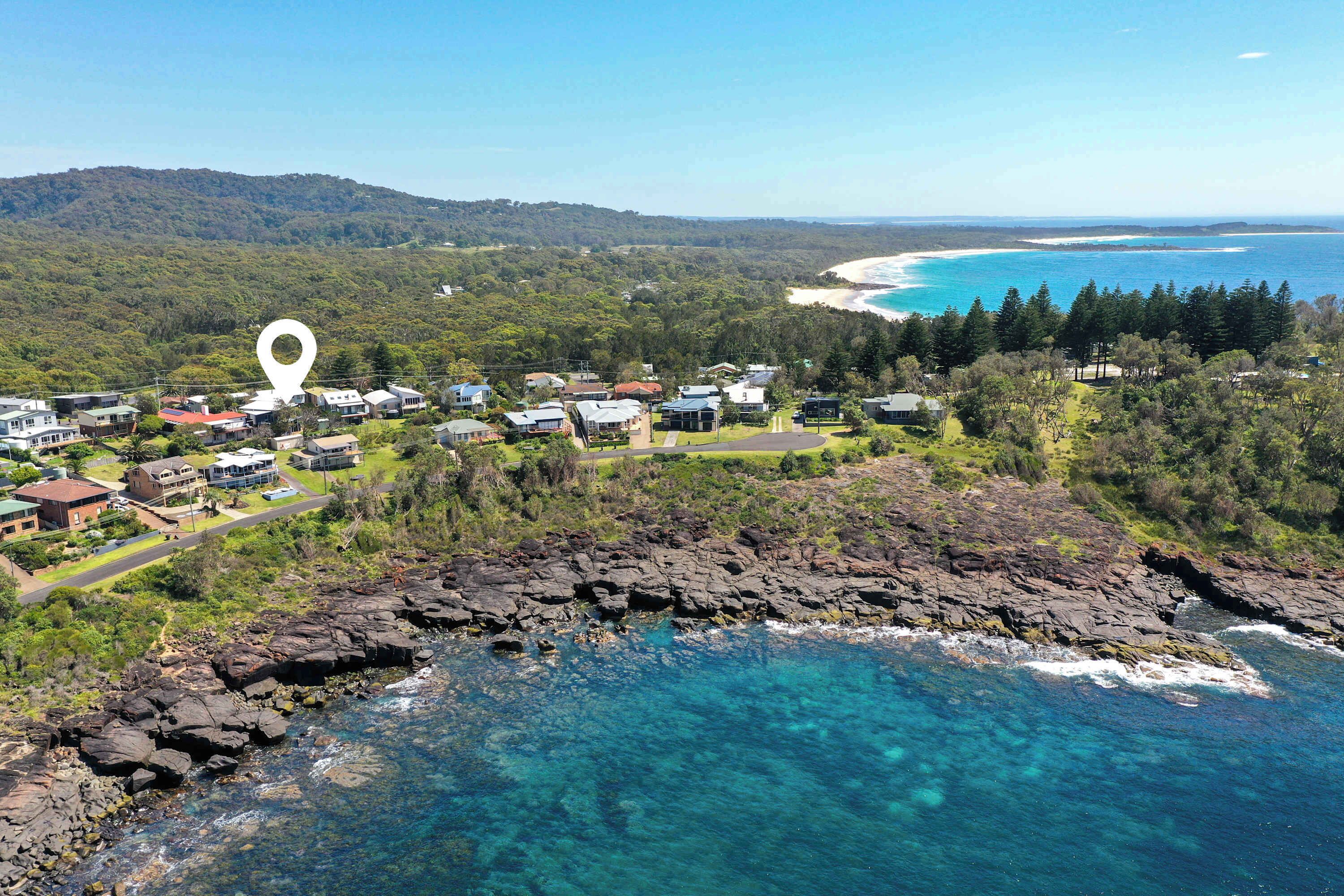 A coastal town with houses near the beach and rocky coastline.