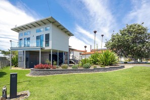 Ein modernes, zweistöckiges Haus mit Balkon, gepflegtem Rasen und verschiedenen Pflanzen.