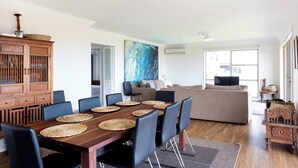 Un coin repas avec une table en bois, des chaises noires et des sets de table en fibres tressées.