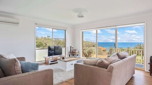 Un salon spacieux doté d’une grande fenêtre donnant sur la mer. On y trouve un canapé, une table basse et un téléviseur.
