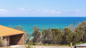 Une propriété située sur la côte, avec un bâtiment en briques, une allée pavée et une vue sur la mer.